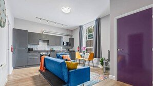 Eine moderne Wohnung mit blauem Sofa, Küche, Essbereich und einer violetten Tür.