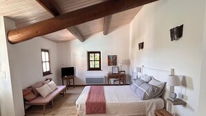Un dormitorio amplio con una cama grande, un banco de madera, una mesita pequeña y una silla.