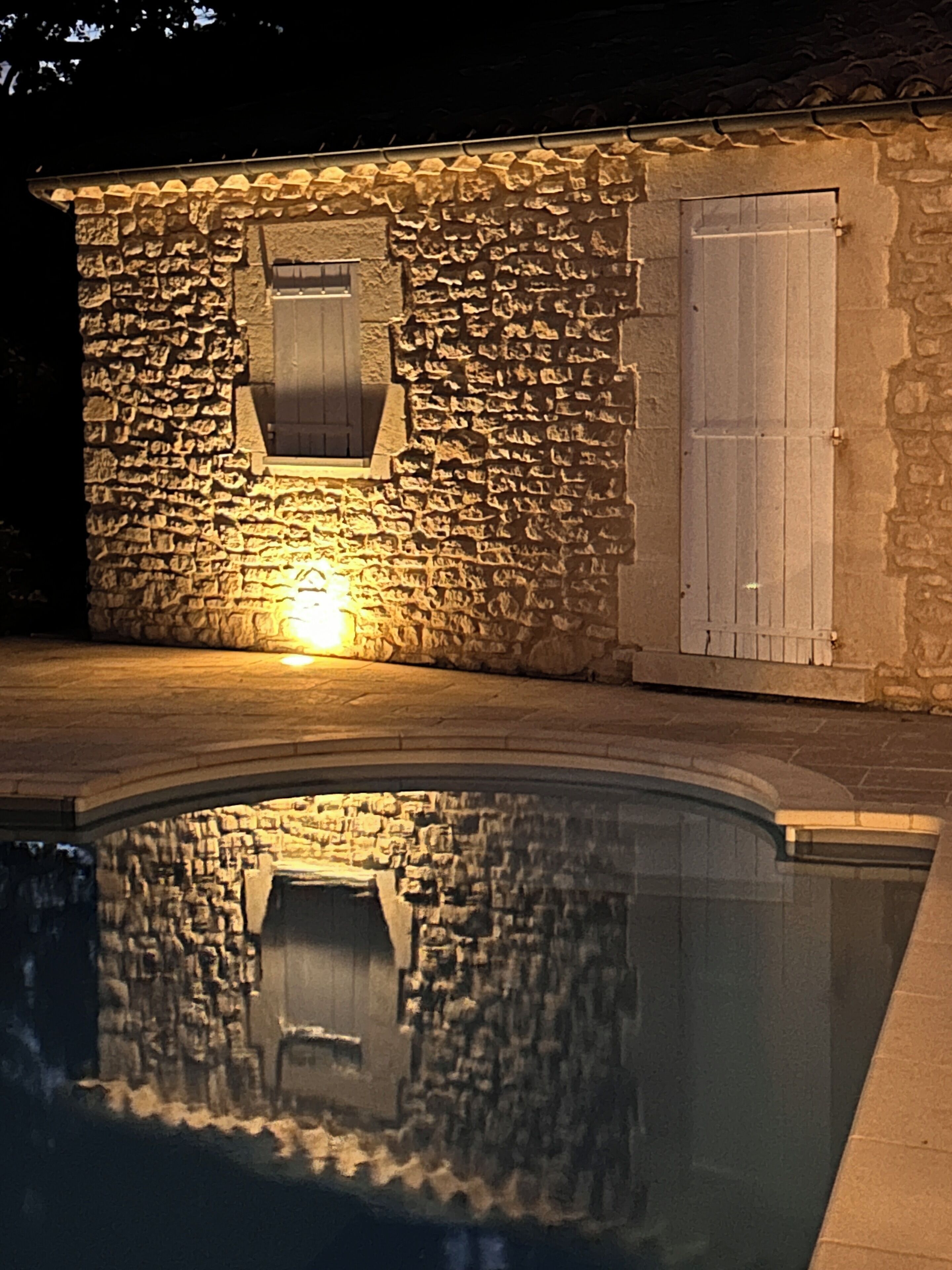 A stone building with a pool reflecting its structure.