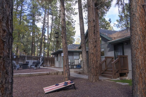 A backyard with a wooden deck, outdoor furniture, and a small building with a porch.