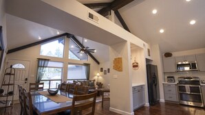 A spacious kitchen with modern appliances, a dining area with wooden furniture, and a large window providing natural light. - Flagstaff Retreat w/ Hot Tub + Fireplace (Flagstaff)