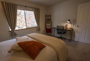 A bedroom with a bed, a desk, and a chair.