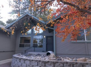 Una casa moderna con chimenea de piedra, ventanas amplias y un porche cubierto.