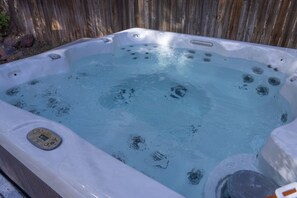 Ein Whirlpool mit Bedienfeld, umgeben von einem Holenzaun.