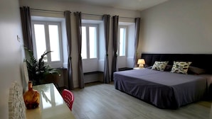 Una habitación de hotel con cama, mesita de noche, lámpara y planta en maceta.