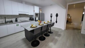 Una cocina moderna con armarios blancos, encimera de granito y una isla central con taburetes de bar.