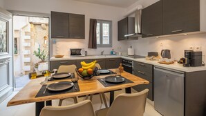 A modern kitchen with dark cabinets, a wooden dining table, and a view of the outside.
