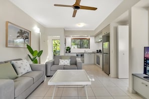 A modern kitchen with a dining area, a ceiling fan, and a large window.