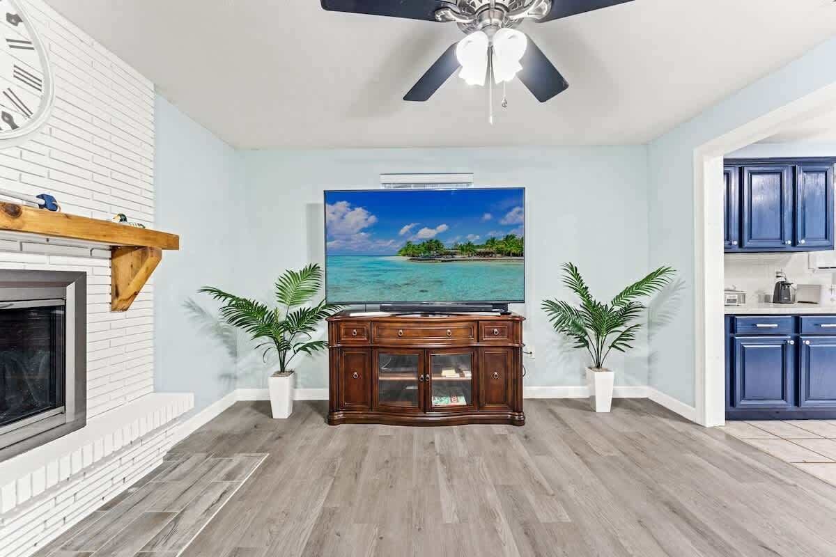 A living room with a fireplace, a television, and a ceiling fan.