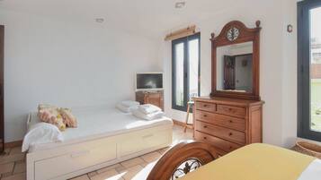 A bedroom with a bed, a dresser, a mirror, a television, and a window.
