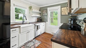 A kitchen with white cabinets, a black refrigerator, and a wooden countertop. - Super Cozy 5 Acre Farmhouse in Luray - Close to Everything (Luray)