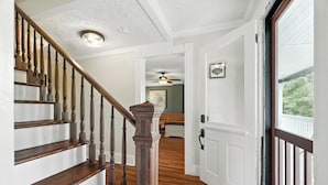 A wooden staircase with a white door at the top leading to a room with a ceiling fan and a framed picture on the wall. - Super Cozy 5 Acre Farmhouse in Luray - Close to Everything (Luray)