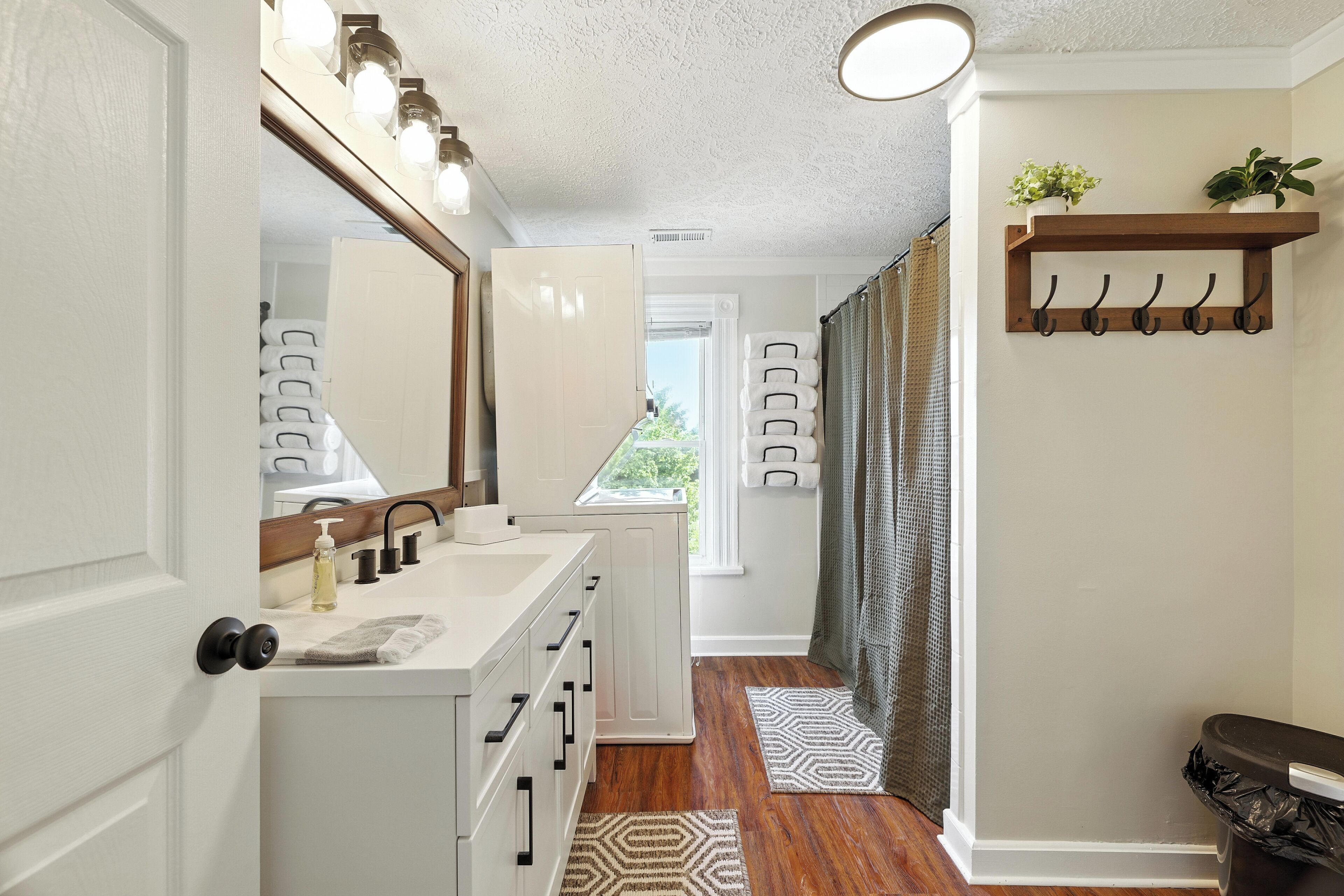 A bathroom with a white vanity, a large mirror, and a shower area.