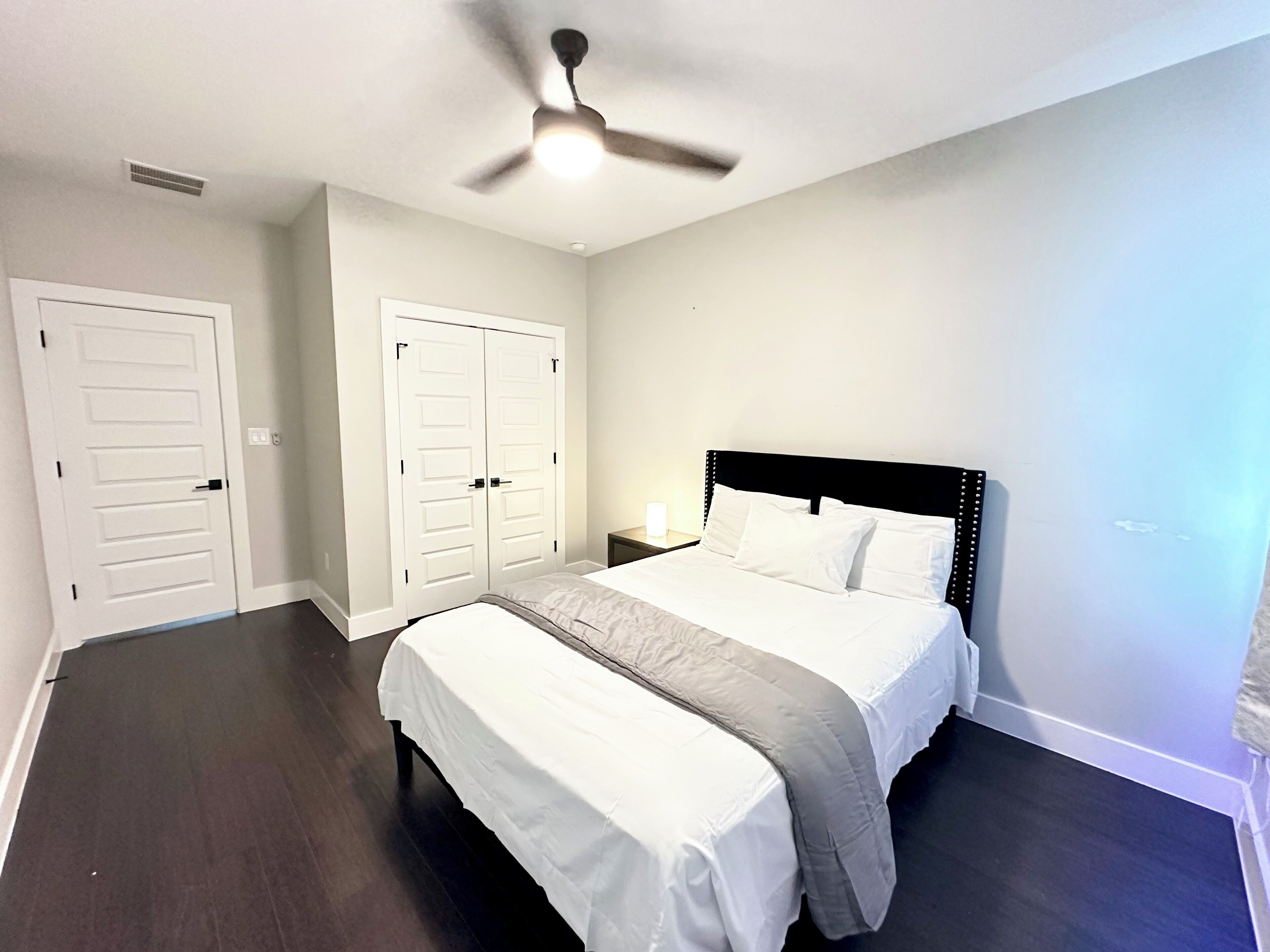 A bedroom with a bed, a bench, a ceiling fan, and a wardrobe.