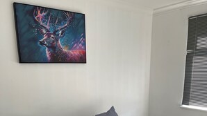 A modern living room with a grey sectional sofa, a beige throw blanket, and a framed abstract painting on the wall. - Privategarden- Freeparking- wd- 2br- Wifi (Glasgow)