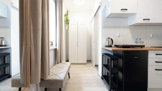 A modern kitchen with white cabinets, a black refrigerator, and a wooden countertop. - A2 Vistula Apartments Kraków (Kraków)