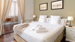A hotel room with a large bed, two bedside tables with lamps, a chair, and a window with sheer curtains. - Apartamento de Tres Habitaciones con Terraza 11B (Barcelona)