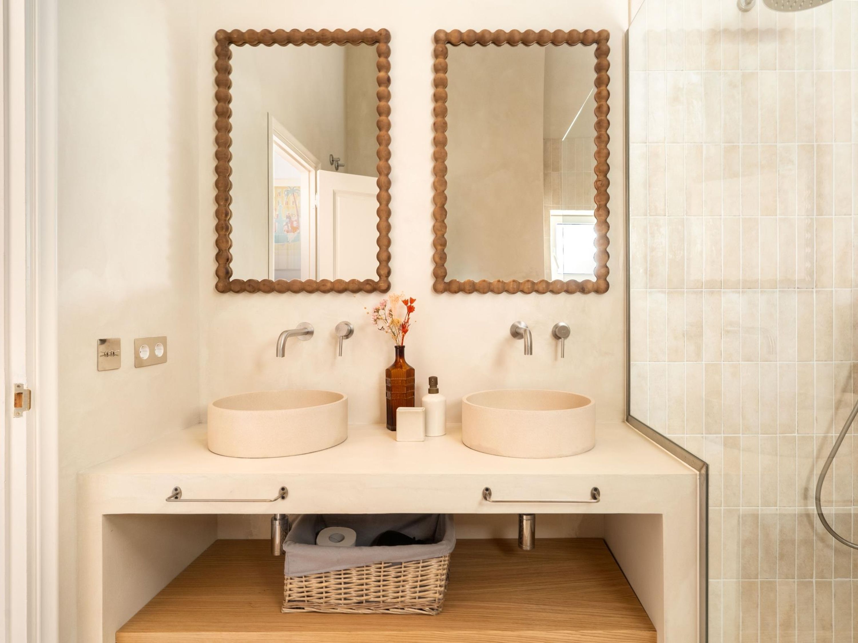 A bathroom with two sinks, a mirror, and a shower.