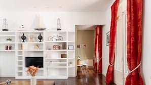 A modern living room with a wooden coffee table, a TV, and a bookshelf filled with various items. - Apartamento de Tres Habitaciones con Terraza 11B (Barcelona)
