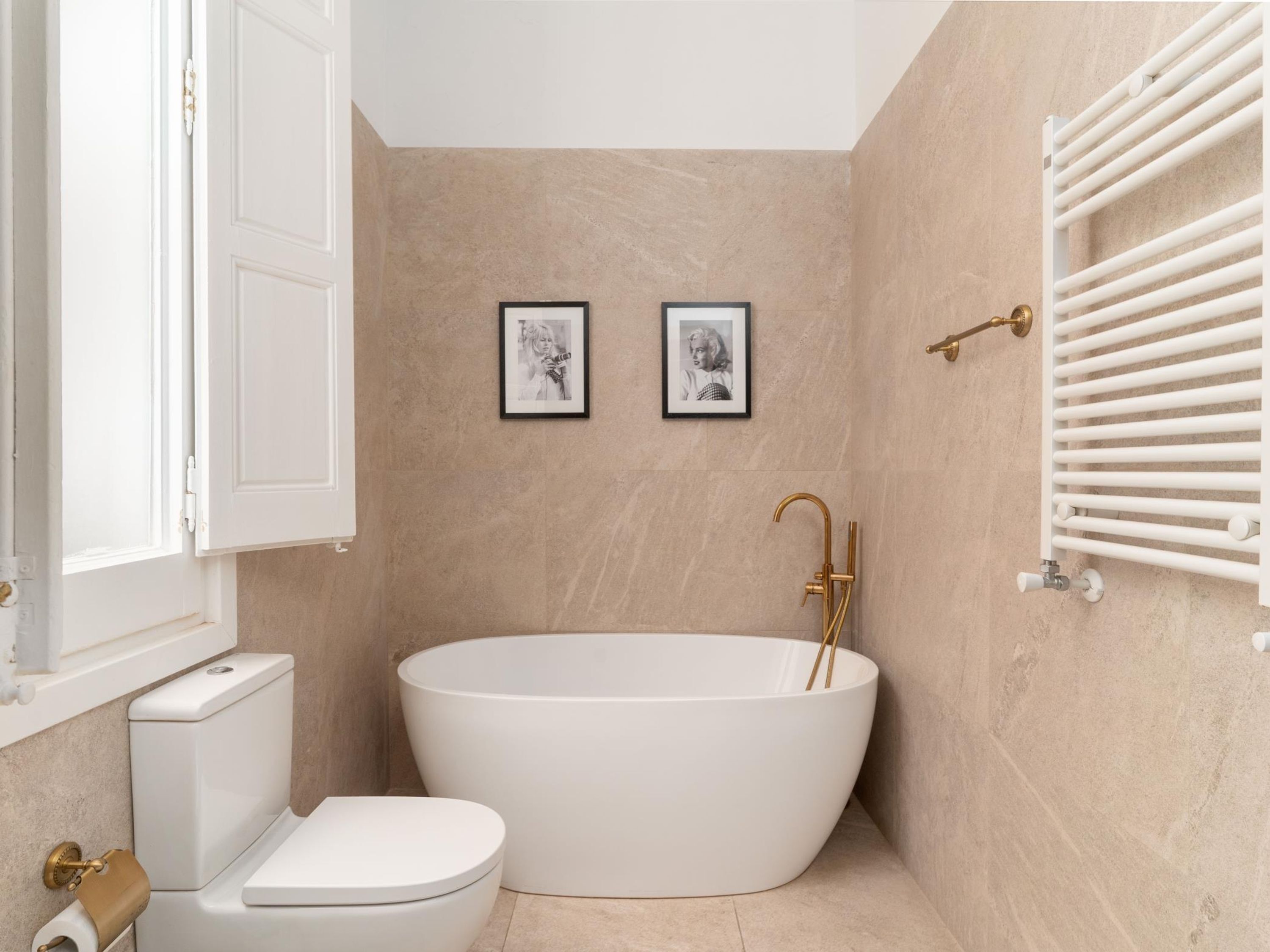 A modern bathroom with a freestanding bathtub, a toilet, and a wall-mounted radiator.