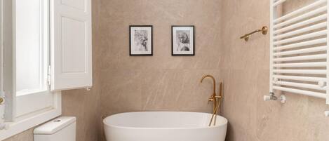 A modern bathroom with a freestanding bathtub, a toilet, and a wall-mounted radiator.