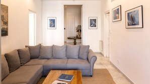 Una sala de estar con un sofá seccional gris, una mesa de centro de madera con un libro y obras de arte enmarcadas en las paredes.