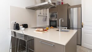 Una cocina moderna con una isla central, electrodomésticos de acero inoxidable y encimera blanca.