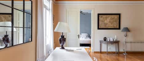 Habitación de hotel con un espejo grande, una mesa blanca, una cama y un radiador.