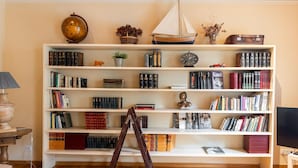 A room with a large bookshelf filled with books, a globe, a ship model, and a ladder. - Apartamento de dos Habitaciones (Barcelona)
