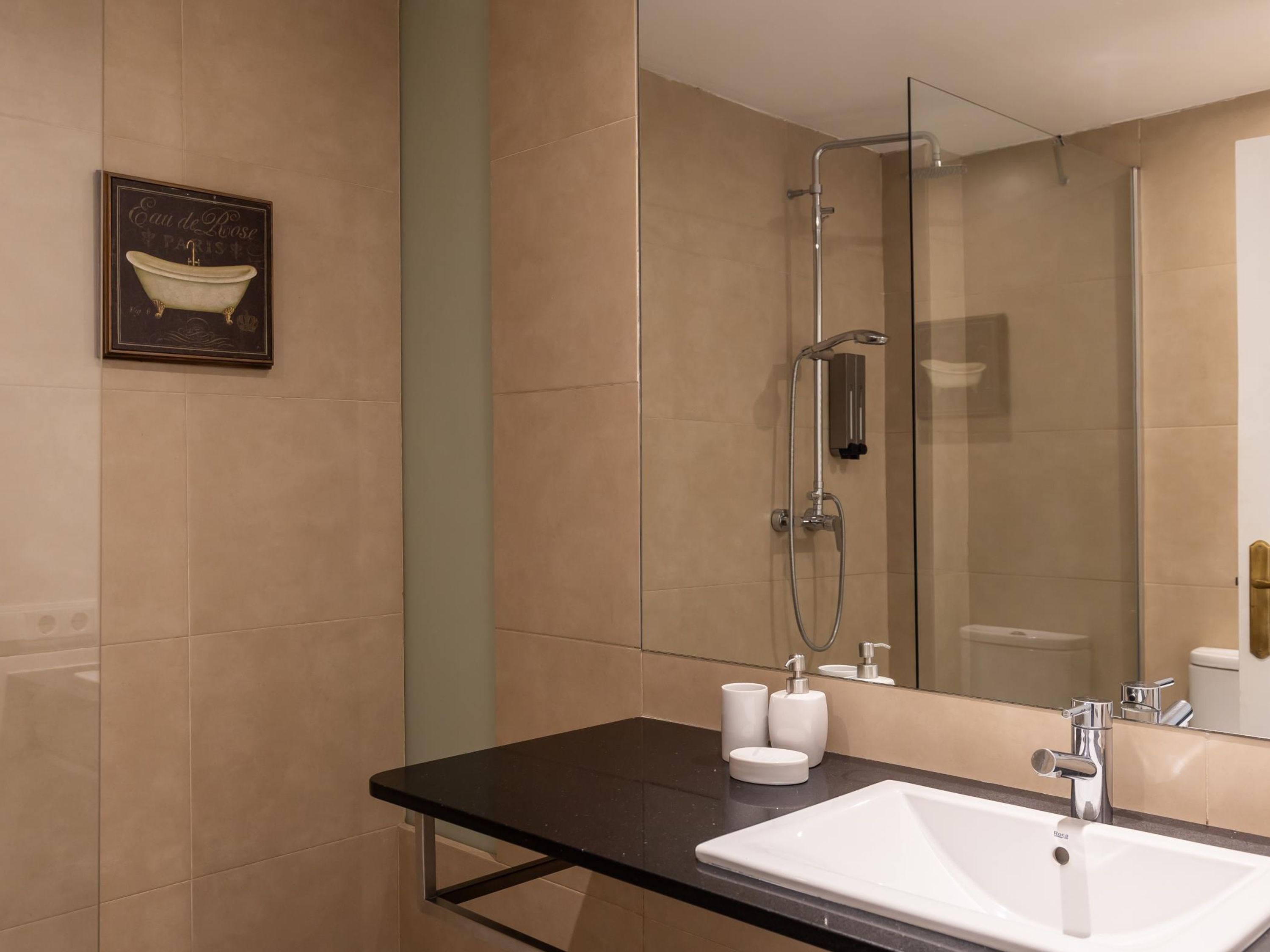 A modern bathroom with a large mirror, a white sink, and a glass-enclosed shower.