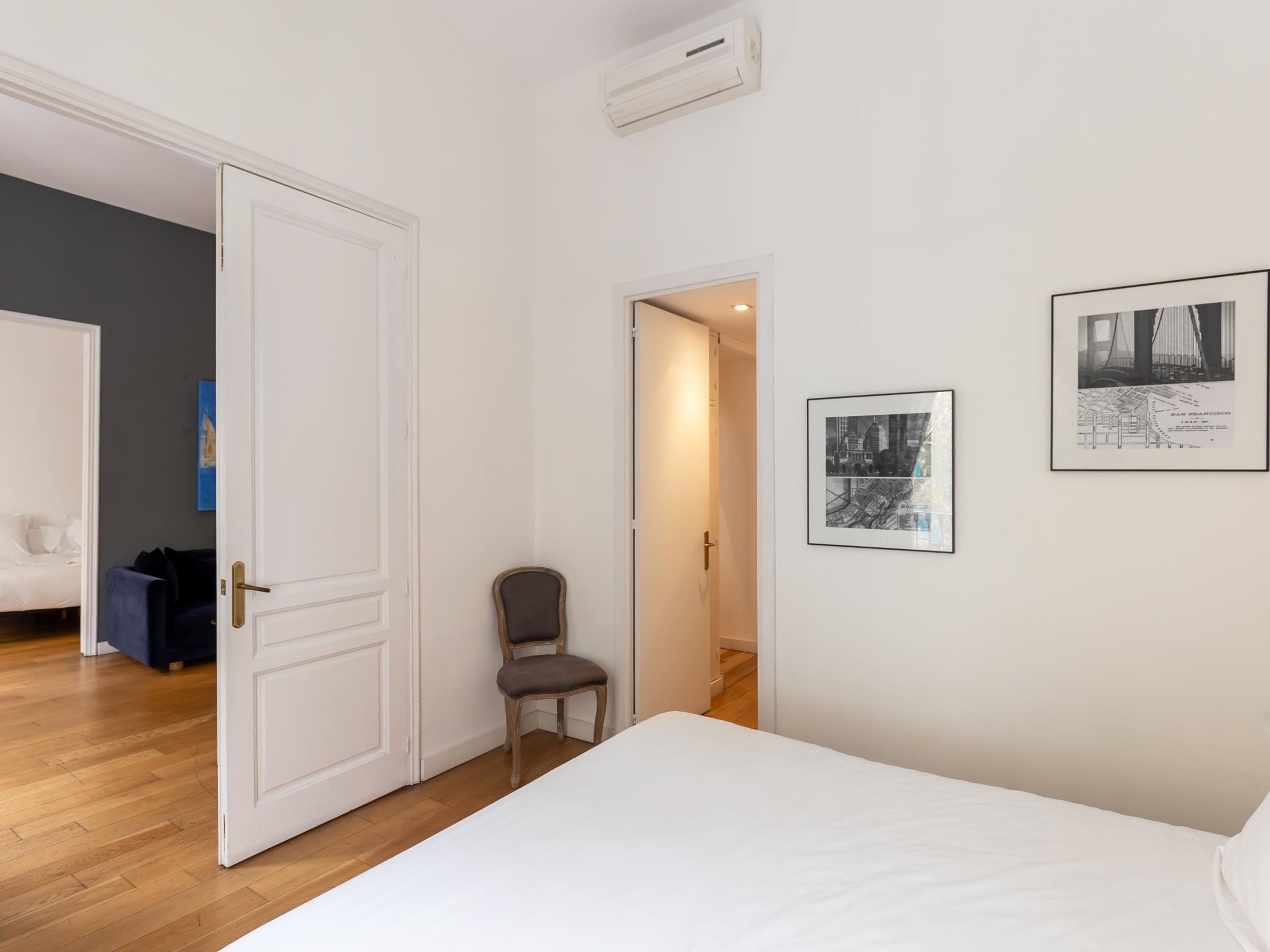 Une chambre à coucher avec un lit, une chaise et deux tableaux encadrés accrochés au mur.