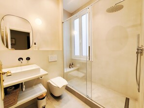 Een moderne badkamer met een douchecabine van glas, een witte wastafel en een spiegel.