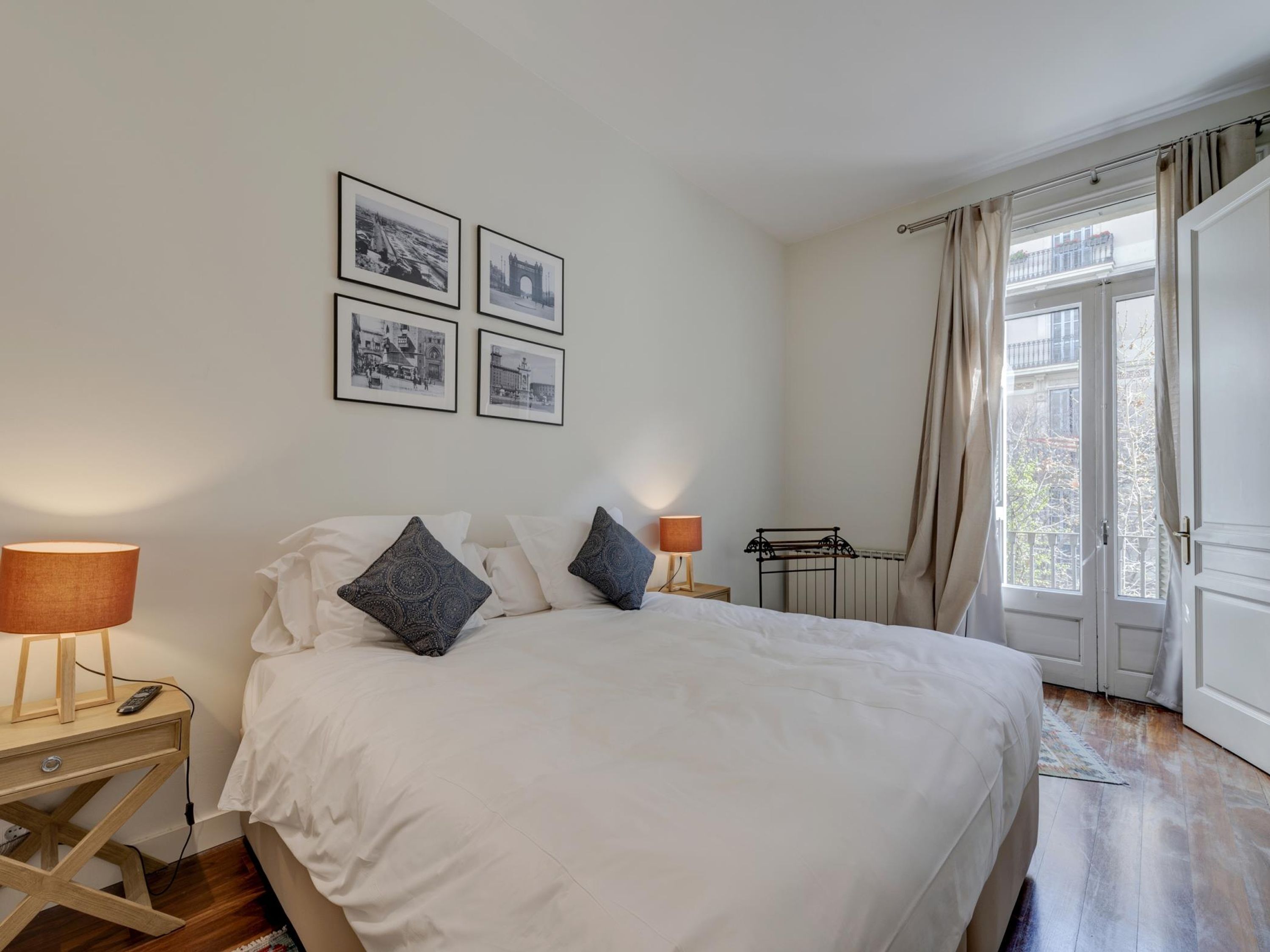 Une chambre à coucher avec un lit, deux lampes de chevet, une table de chevet, un radiateur et une fenêtre avec des rideaux.