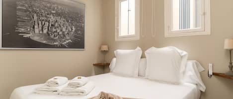 Hotelkamer met een bed, een groot stadsfotografie, twee ramen, een nachtkastje en een lamp.