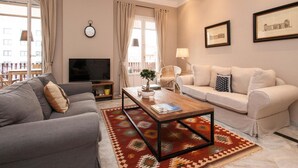 A living room with a grey sofa, a beige sofa, a wooden coffee table, and a patterned rug.