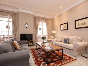 A living room with a grey sofa, a beige sofa, a wooden coffee table, and a patterned rug. - Apto Superior de Tres Habitaciones con Terraza (Barcelona)