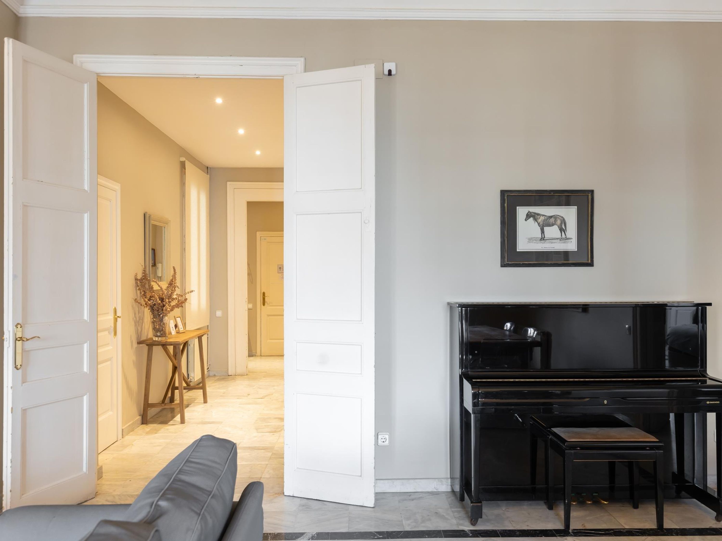 A living room with a piano, a sofa, and a hallway leading to another room.