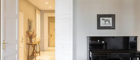 A living room with a piano, a sofa, and a hallway leading to another room.