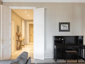 Una sala de estar con un piano, un sofá y un pasillo que conduce a otra habitación.