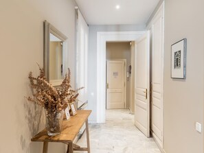 A hallway with a wooden bench, a mirror, and a door leading to another room.
