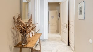 A hallway with a wooden bench, a mirror, and a door leading to another room.