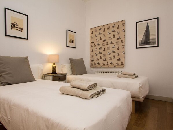 Ein Hotelzimmer mit zwei Betten, einem Nachttisch mit Lampe, einer Wand mit gerahmten Bildern und einem Heizkörper.