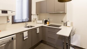 A modern kitchen with a dishwasher, a window, a sink, and a built-in oven. - Apartamento Deluxe de Tres Habitaciones (Barcelona)