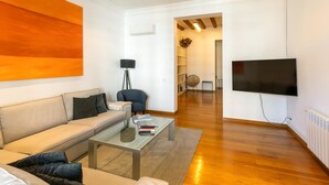A modern living room with a sofa, coffee table, and a flat-screen TV. - Apartamento de Tres Habitaciones con Terraza 21B (Barcelona)