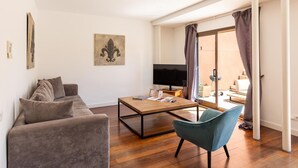 A modern living room with a sofa, a coffee table, a TV, and a view of the outside. - Apartamento Tico con Terraza (Barcelona)