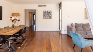 A spacious living area with a wooden dining table, a blue armchair, and a sofa. - Apartamento Tico con Terraza (Barcelona)