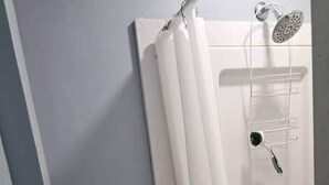 Eine Dusche mit Duschbrause, Handbürste und Handtuchhalter.