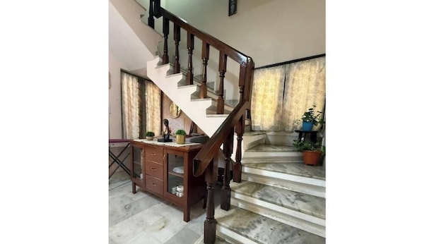 Un escalier avec des balustrades en bois menant à un palier où se trouvent un bureau et des plantes en pot.
