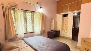 Une chambre à coucher avec un lit, une armoire, un miroir et une fenêtre avec des rideaux.