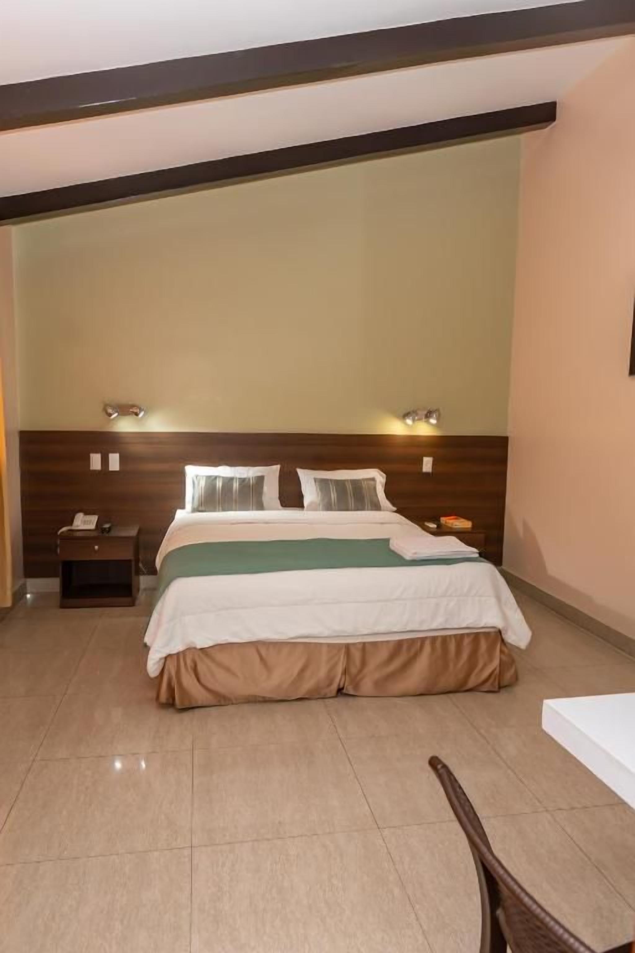 A hotel room with a bed, bedside tables, and a nightstand.